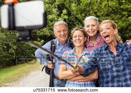 Group of friends taking self portrait, using selfie stick and smartphone View Large Photo Image Stock Photography - Group of friends taking self portrait, using selfie stick and smartphone. Fotosearch