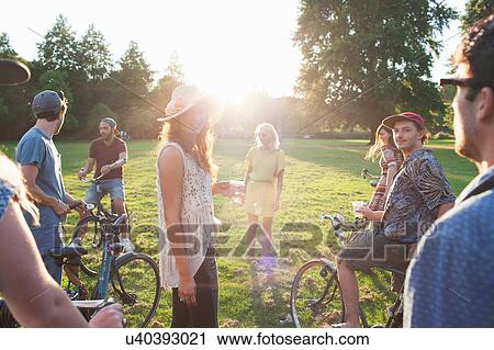 Group of party going adults arriving in park on bicycles at sunset View Large Photo Image Stock Image - Group of party going adults arriving in park on bicycles at sunset. Fotosearch