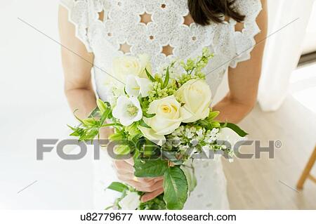 Stock Photo - High angle view of mature woman wearing broderie anglaise holding flower arrangements. Fotosearch