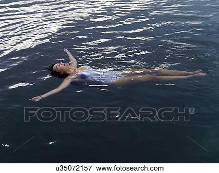 High angle view of woman floating on back in water arms outstretched looking up View Large Photo Image Stock Photo - High angle view of woman floating on back in water arms outstretched looking up. Fotosearch