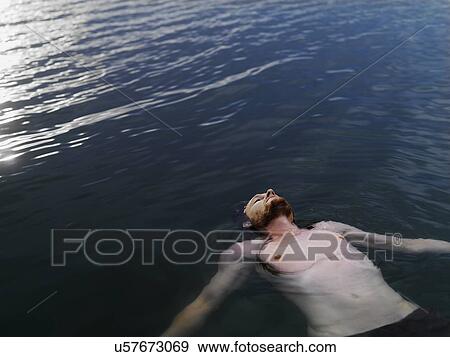 High angle view of young man floating on back in water arms outstretched looking up View Large Photo Image Stock Photo - High angle view of young man floating on back in water arms outstretched looking up. Fotosearch