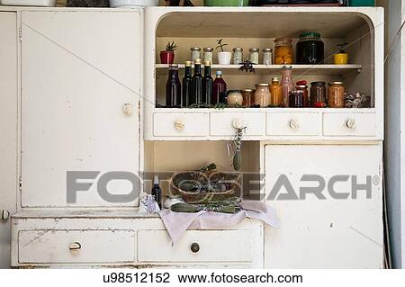 Stock Image - Jars and bottles of home-made food on retro style kitchen cabinet. Fotosearch