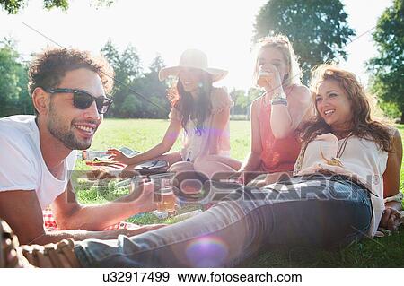 Stock Photo - Man and women drinking and relaxing at park party. Fotosearch
