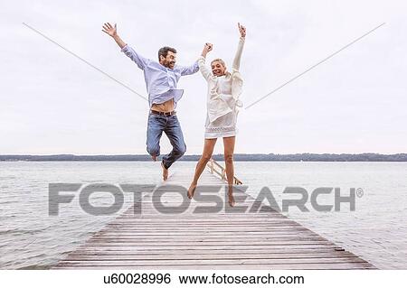 Mature couple jumping for joy on pier View Large Photo Image Stock Photograph - Mature couple jumping for joy on pier. Fotosearch
