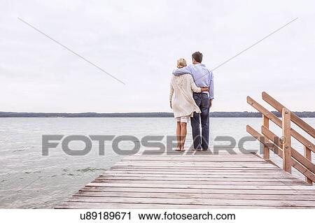 Mature couple standing on pier, looking at view, rear view View Large Photo Image Stock Image - Mature couple standing on pier, looking at view, rear view. Fotosearch