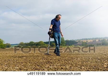 Mature man wearing headphones searching muddy field using metal detector View Large Photo Image Stock Photo - Mature man wearing headphones searching muddy field using metal detector. Fotosearch