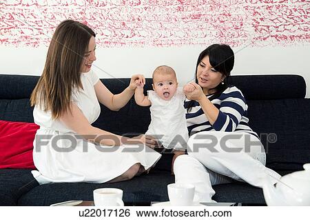 Mature woman and daughter playing with baby girl on sofa View Large Photo Image Stock Photograph - Mature woman and daughter playing with baby girl on sofa. Fotosearch