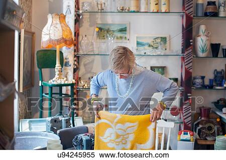 Mature woman folding yellow blanket in vintage shop View Large Photo Image Stock Photography - Mature woman folding yellow blanket in vintage shop. Fotosearch