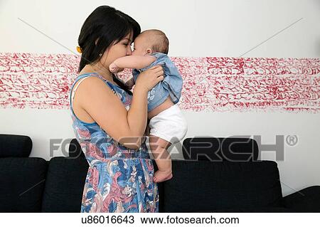 Mature woman holding baby granddaughter in living room View Large Photo Image Stock Image - Mature woman holding baby granddaughter in living room. Fotosearch