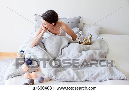 Mature woman in bed underneath quilt with decorative lights hand over mouth looking away View Large Photo Image Stock Image - Mature woman in bed underneath quilt with decorative lights hand over mouth looking away. Fotosearch