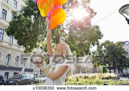 Mature woman, outdoors, holding bunch of balloons View Large Photo Image Stock Image - Mature woman, outdoors, holding bunch of balloons. Fotosearch