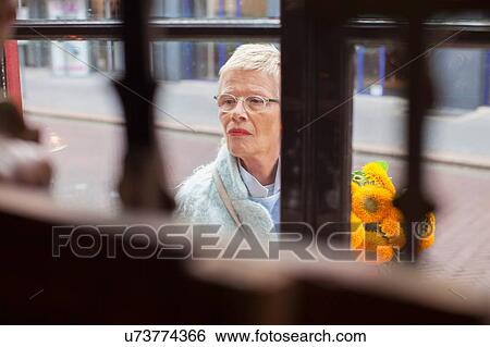 Mature woman with bunch of yellow flowers window shopping View Large Photo Image Stock Photograph - Mature woman with bunch of yellow flowers window shopping. Fotosearch