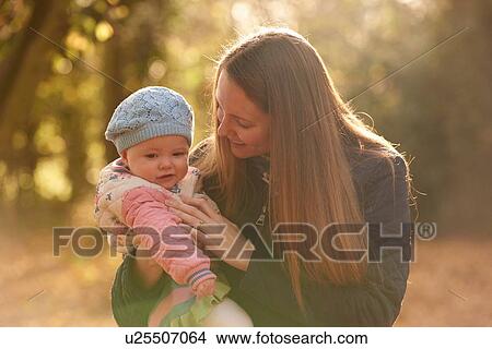 Mid adult woman and baby daughter looking down in autumn park View Large Photo Image Picture - Mid adult woman and baby daughter looking down in autumn park. Fotosearch