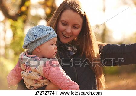 Mid adult woman and baby daughter looking away in autumn park View Large Photo Image Stock Image - Mid adult woman and baby daughter looking away in autumn park. Fotosearch
