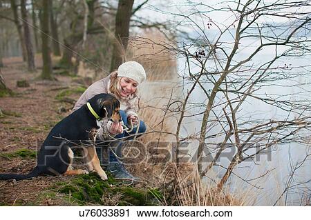 Mid adult woman crouching with her dog on riverbank View Large Photo Image Stock Image - Mid adult woman crouching with her dog on riverbank. Fotosearch