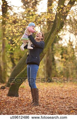 Mid adult woman holding up baby daughter in autumn park View Large Photo Image Stock Photograph - Mid adult woman holding up baby daughter in autumn park. Fotosearch
