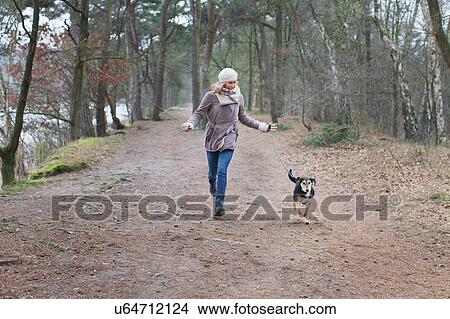 Mid adult woman running with her dog in forest View Large Photo Image Picture - Mid adult woman running with her dog in forest. Fotosearch