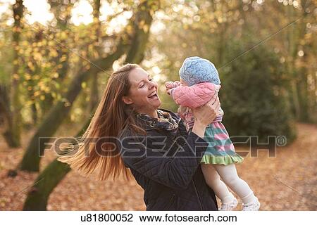 Mid adult woman swinging baby daughter in autumn park View Large Photo Image Stock Image - Mid adult woman swinging baby daughter in autumn park. Fotosearch