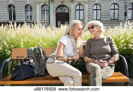 Mother and daughter sitting on bench together, outdoors View Large Photo Image Stock Photo - Mother and daughter sitting on bench together, outdoors. Fotosearch