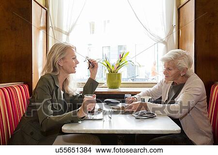 Picture - Mother and daughter sitting together in cafe. Fotosearch