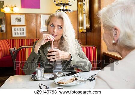 Mother and daughter sitting together in cafe View Large Photo Image Stock Image - Mother and daughter sitting together in cafe. Fotosearch
