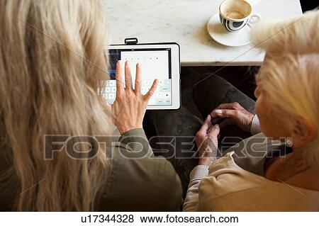 Mother and daughter sitting together in cafe, looking at digital tablet, rear view View Large Photo Image Stock Photo - Mother and daughter sitting together in cafe, looking at digital tablet, rear view. Fotosearch