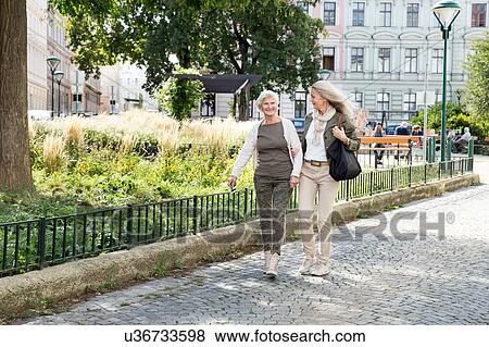 Stock Photo - Mother and daughter walking along street together. Fotosearch