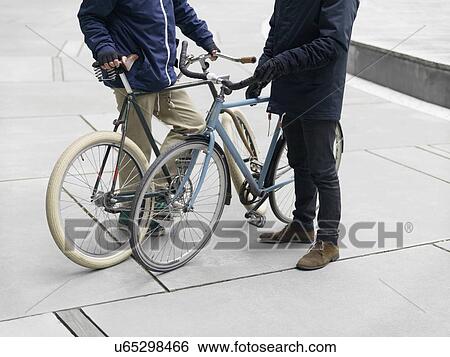Neck down view of urban cyclists standing beside bicycle View Large Photo Image Stock Photograph - Neck down view of urban cyclists standing beside bicycle. Fotosearch