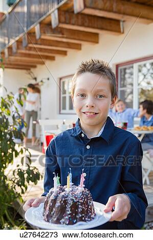 Portrait of boy carrying birthday cake on patio View Large Photo Image Stock Image - Portrait of boy carrying birthday cake on patio. Fotosearch
