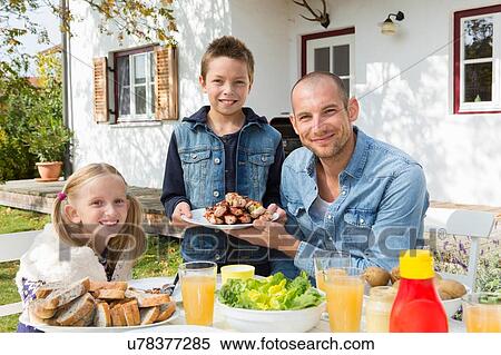 Portrait of father and children at garden barbecue table View Large Photo Image Stock Photography - Portrait of father and children at garden barbecue table. Fotosearch