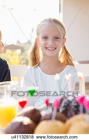 Portrait of happy girl with birthday cake at patio table View Large Photo Image Stock Photo - Portrait of happy girl with birthday cake at patio table. Fotosearch