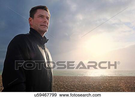 Portrait of mature man looking away from sunlit shingle beach View Large Photo Image Stock Photo - Portrait of mature man looking away from sunlit shingle beach. Fotosearch