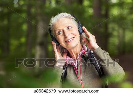 Portrait of senior woman wearing headphones, standing in forest View Large Photo Image Stock Photo - Portrait of senior woman wearing headphones, standing in forest. Fotosearch