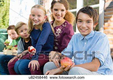 Portrait of teenagers and children sitting on patio eating apples View Large Photo Image Stock Photograph - Portrait of teenagers and children sitting on patio eating apples. Fotosearch