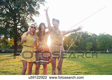 Portrait of three young women friends wrapping themselves in streamers at party in park View Large Photo Image Stock Image - Portrait of three young women friends wrapping themselves in streamers at party in park. Fotosearch