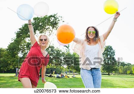 Portrait of two young women dancing with balloons at park party View Large Photo Image Stock Image - Portrait of two young women dancing with balloons at park party. Fotosearch