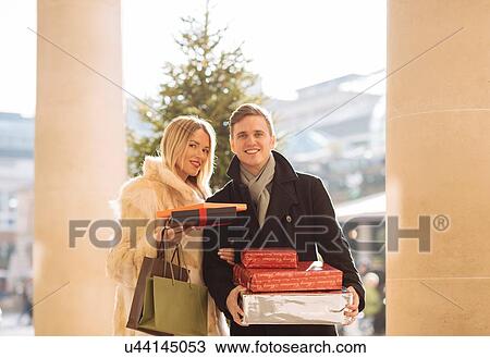 Portrait of young couple carrying xmas gifts in Covent Garden, London, UK View Large Photo Image Stock Image - Portrait of young couple carrying xmas gifts in Covent Garden, London, UK. Fotosearch