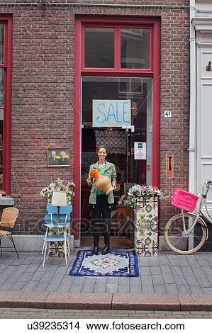 Portrait of young female customer holding jug outside vintage shop View Large Photo Image Picture - Portrait of young female customer holding jug outside vintage shop. Fotosearch