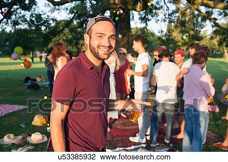 Portrait of young man at crowded party in park at sunset View Large Photo Image Stock Image - Portrait of young man at crowded party in park at sunset. Fotosearch