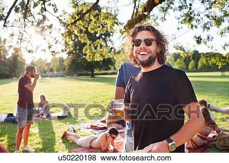 Portrait of young man drinking beer at group party picnic in park View Large Photo Image Stock Photo - Portrait of young man drinking beer at group party picnic in park. Fotosearch