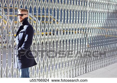 Portrait of young man standing by fence View Large Photo Image Picture - Portrait of young man standing by fence. Fotosearch