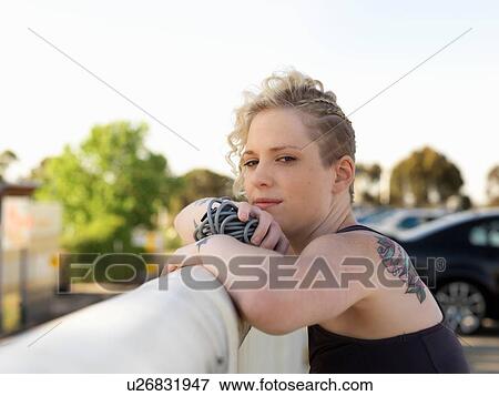 Portrait of young woman holding skipping rope leaning against urban railing View Large Photo Image Stock Photo - Portrait of young woman holding skipping rope leaning against urban railing. Fotosearch