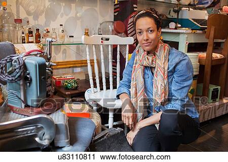 Stock Image - Portrait of young woman in vintage shop. Fotosearch