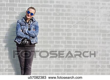 Portrait of young woman leaning against wall, outdoors View Large Photo Image Stock Image - Portrait of young woman leaning against wall, outdoors. Fotosearch