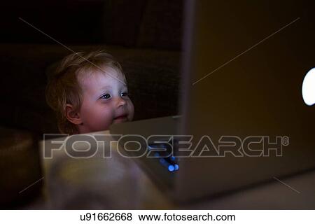 Stock Photo - Preschool girl looking at laptop smiling. Fotosearch