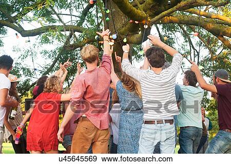 Rear view of adult friends cheering and dancing at park party View Large Photo Image Stock Photo - Rear view of adult friends cheering and dancing at park party. Fotosearch