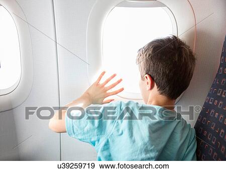 Rear view of boy looking and waving through airplane window View Large Photo Image Stock Photo - Rear view of boy looking and waving through airplane window. Fotosearch