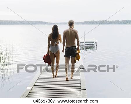 Rear view of couple wearing swimsuits, walking down pier carrying towels, Copenhagen, Denmark View Large Photo Image Stock Photo - Rear view of couple wearing swimsuits, walking down pier carrying towels, Copenhagen, Denmark. Fotosearch
