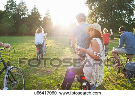 Rear view of party going adults in park on bicycles at sunset View Large Photo Image Stock Image - Rear view of party going adults in park on bicycles at sunset. Fotosearch