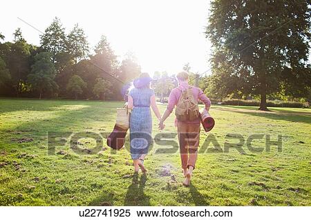 Rear view of romantic young couple carrying rug in park View Large Photo Image Stock Photography - Rear view of romantic young couple carrying rug in park. Fotosearch